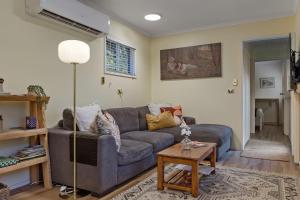 a living room with a couch and a table at Fernvale Cottage - An Enchanting Mountainside Oasis in Lenah Valley