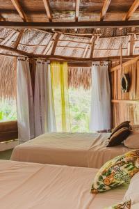 a bedroom with two beds and a thatched roof at Magic Green Dentro del Parque Tayrona in El Zaino