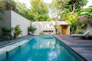 a swimming pool with a wooden deck next to a house at Villa Athena in Seminyak
