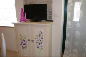 a tv on a cabinet with purple flowers on it at Studio Stella in Rovinj