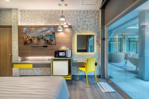 a bedroom with a bed and a desk with a microwave at Qiu Hotel Sukhumvit SHA Plus in Bangkok