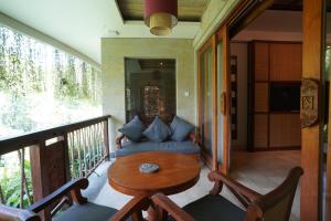 a porch with a couch and a table on a balcony at Kenran Resort Ubud By Soscomma in Ubud