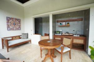 a living room with a table and a kitchen at Kenran Resort Ubud By Soscomma in Ubud