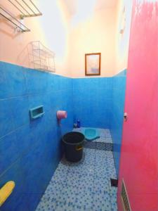a blue bathroom with a toilet and a bucket at Aloha Living in Pangandaran