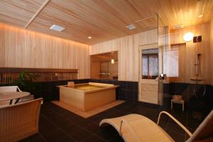 a bathroom with a tub and a table and chairs at Suizantei Club Jozankei-Adults Only in Jozankei
