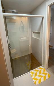 een glazen douchedeur met een geel-wit geblokt kleed bij Studio Próximo ao metrô Butantã in Sao Paulo