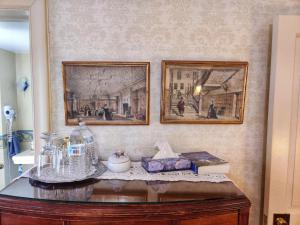 zwei gerahmte Bilder an einer Wand mit einem Tisch in der Unterkunft Montague Inn Bed & Breakfast in Saginaw