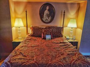 1 dormitorio con 1 cama con 2 lámparas y una foto en la pared en Montague Inn Bed & Breakfast, en Saginaw