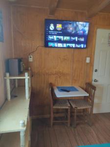 Zimmer mit einem Tisch und einem TV an der Wand in der Unterkunft Mini Loft in El Quisco