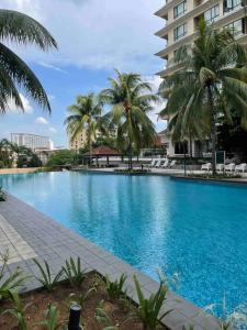 a large swimming pool with palm trees and a building at Cozy 1 Bedroom Condo w Balcony in Shah Alam