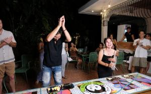 a man holding his hands in the air in front of a table at Mad Monkey Dumaguete in Dumaguete