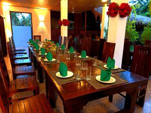 una larga mesa de madera con servilletas y vasos verdes en Even Beach Resort en Wayikkal