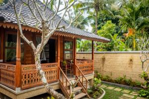 ein Holzhaus mit einem Baum davor in der Unterkunft Toya Sutra Villa in Tampaksiring