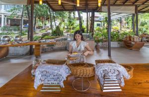 Secret Cliff Resort & Restaurant - SHA Plus في شاطئ كارون: امرأة تجلس على طاولة مع طبق من الطعام