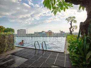 een zwembad met een persoon in het water bij Apartemen Vida View Makassar by drAnca in Makassar