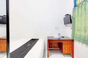 a bedroom with a bed and a desk and a tv at Capital O 92929 Hotel New Tirta Kencana Syariah in Tegal
