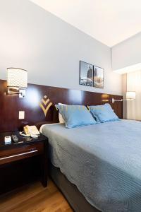 una camera da letto con un grande letto con cuscini blu di ELEGANCE SUÍTES BERRINI a San Paolo