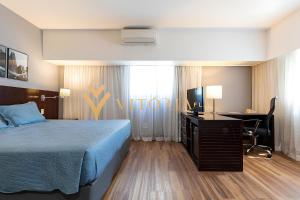 una camera d'albergo con letto, scrivania e TV di ELEGANCE SUÍTES BERRINI a San Paolo