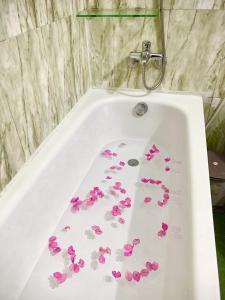 a bath tub filled with pink flowers in a bathroom at Jade Hotel in Hue