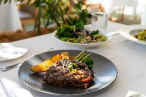 a plate of food with a steak and vegetables on a table at Pullman Cairns International in Cairns +170 photos