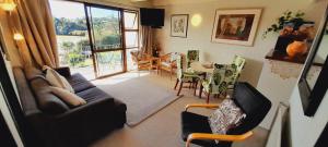 een woonkamer met een bank, stoelen en een tafel bij Waterfalls Estate - Falls Motel & Waterfront Campground in Paihia