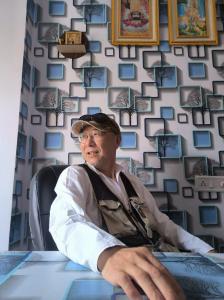 um homem sentado numa mesa em frente a uma parede com imagens em Shree Krishna Hotel em Udaipur