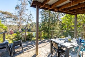 une terrasse en bois avec une table et des chaises. dans l'établissement Katoomba Falls Cottage, à Katoomba