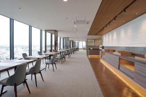 a row of tables and chairs in a room with windows at Hotel Marroad Tsukuba in Tsuchiura