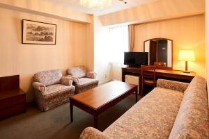 a hotel room with a couch and chairs and a desk at Hotel Marroad Tsukuba in Tsuchiura