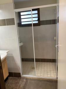 a shower with a glass door in a bathroom at Michelle’s flat by the Sea in Noumea