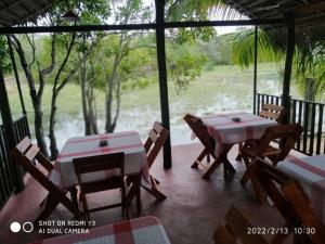porche con mesas y sillas y vistas al río en kingfish villa and restaurant, en Ranna