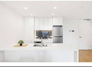 a white kitchen with a sink and a refrigerator at One Bedroom with Roof Top Pool in Sydney