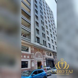 Cairo Taj Dokki Families Tower في القاهرة: مبنى طويل وبه سيارات متوقفة أمامه