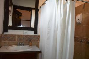 ein Badezimmer mit einem Waschbecken und einem weißen Duschvorhang in der Unterkunft Samay Kirutoa Lodge in Quilotoa
