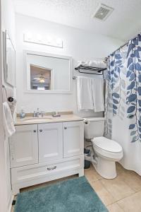 La salle de bains est pourvue d'un lavabo blanc et de toilettes. dans l'établissement Surfside Cottage near Navarre Beach, à Navarre