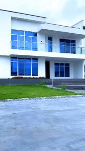 un edificio blanco con ventanas azules y aparcamiento en Contemporary 4-Bedroom Villa with VR Room and Starlink Internet - Ifemide Estates, en Akure