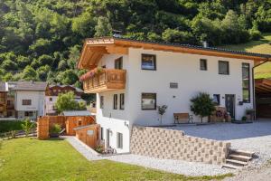 duży biały dom z drewnianym balkonem w obiekcie Ferienwohnung Alpenland - schönes, neues Apartment w Neustift im Stubaital