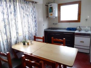 cocina con mesa de madera, mesa y sillas en Departamento en Villa Gesell en Villa Gesell