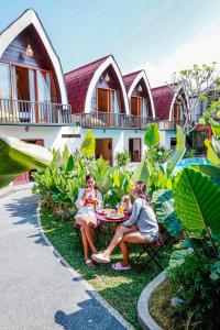 Dos mujeres sentadas en una mesa frente a una casa en Neo Bintang Bungalow Cafe and Pool, en Sanur
