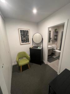 Ruckers Hill Northcote Penthouse في ملبورن: حمام به كرسي أخضر ومرآة
