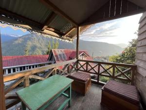 balcón con mesa, bancos y vistas en Odyssey's Darap Eco Retreat, en Pelling