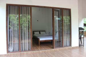 een kamer met glazen schuifdeuren met een bed erin bij Cinty Guest House in Dambulla
