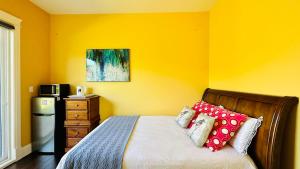a yellow bedroom with a bed with red pillows at Quiet Room in Richmond in Richmond