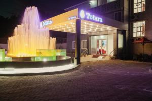 a building with a fountain in front of a store at Hotel Totara in Dar es Salaam