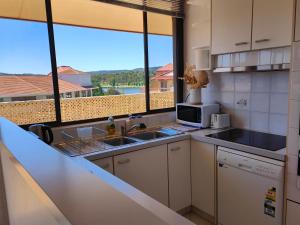 a kitchen with a sink and a microwave at Tuggeranong Short Stay #07C - Sleeps 6 in Canberra