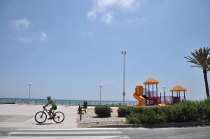 a person riding a bike on a sidewalk near the beach at Hotel Castilla Alicante in Alicante