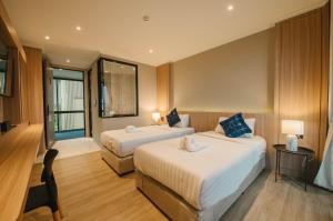 a hotel room with two beds and a window at Carrara Hotel Hatyai in Hat Yai