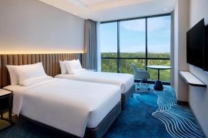 a hotel room with two beds and a tv at Novotel Yogyakarta International Airport Kulon Progo in Yogyakarta +5 photos