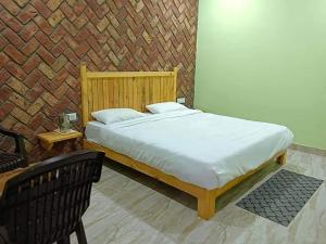 een slaapkamer met een bed en een bakstenen muur bij Shri Jai Krishna Homestay in Rāmnagar