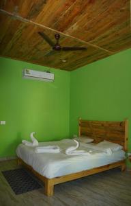 Schlafzimmer mit einem Bett mit grünen Wänden und einer Decke in der Unterkunft Shri Jai Krishna Homestay in Rāmnagar